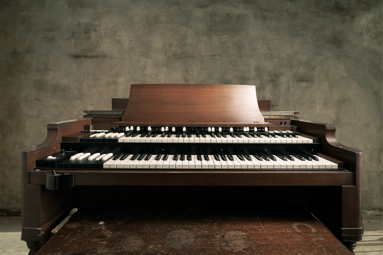 A Hammond B3 organ set against a textured gray concrete wall.
